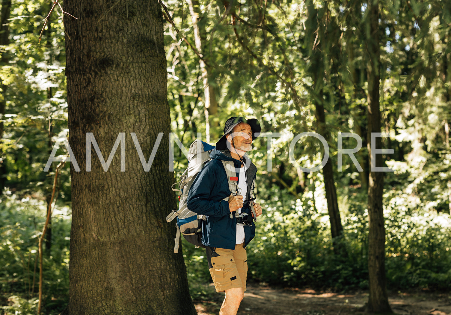 Senior man with backpack and hiking clothes walking in forest. Mature male enjoying the view while walking in forest.