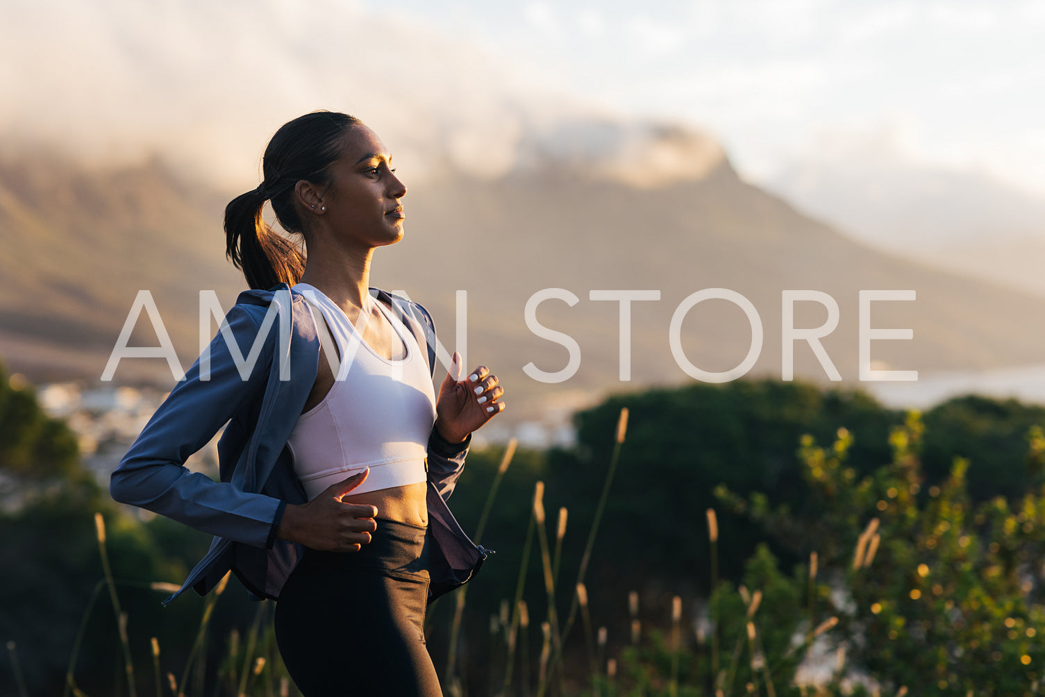 Side view of a young slim female jogging outdoors at a stunning sunset