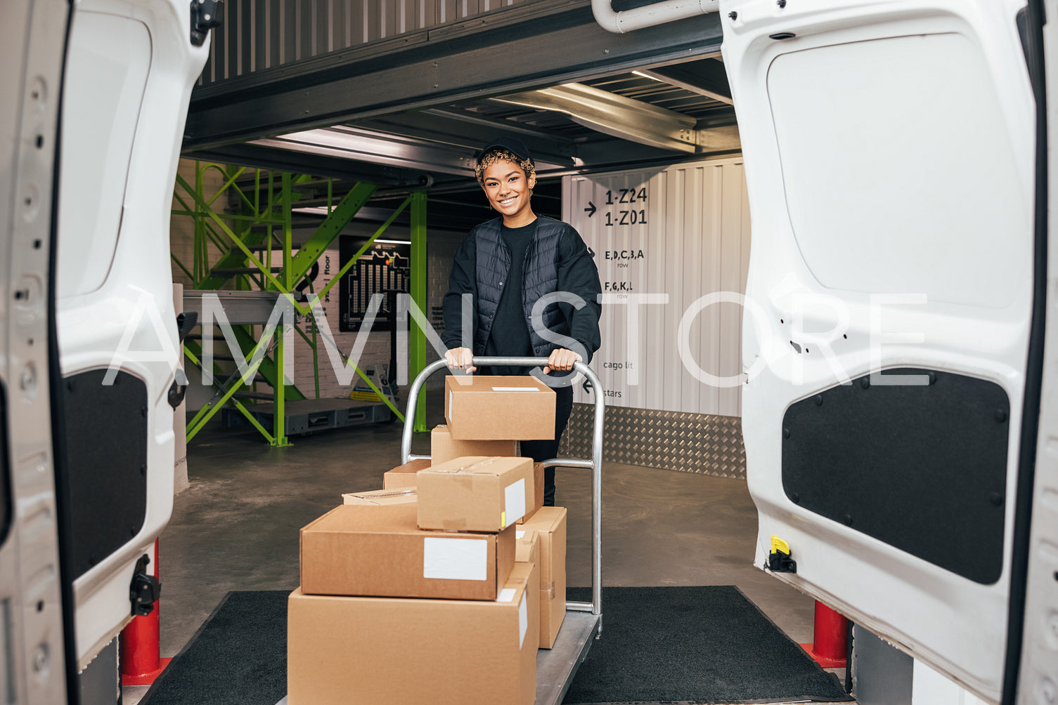 Smiling woman in uniform standing in warehouse with cart prepari