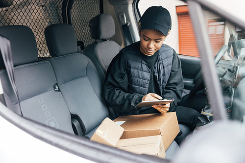 Woman in a uniform of a delivery company checking information on