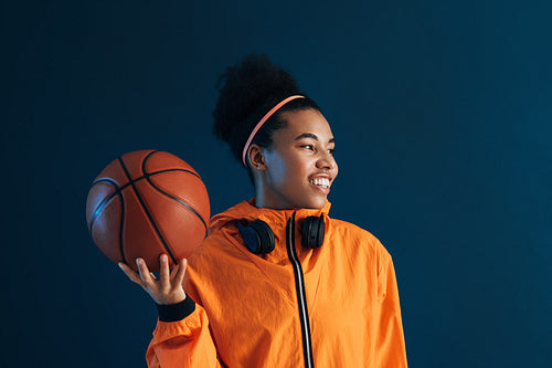 Smiling female basketball player with headphones looking away in the studio