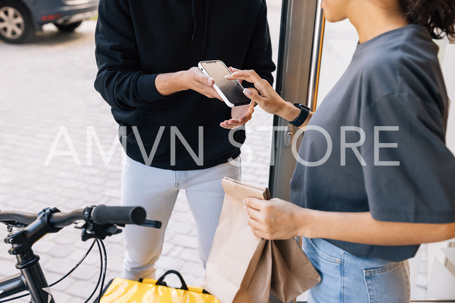 Woman receiving food delivery at the doorway. Midsection of an unrecognizable woman making a sign on a smartphone.