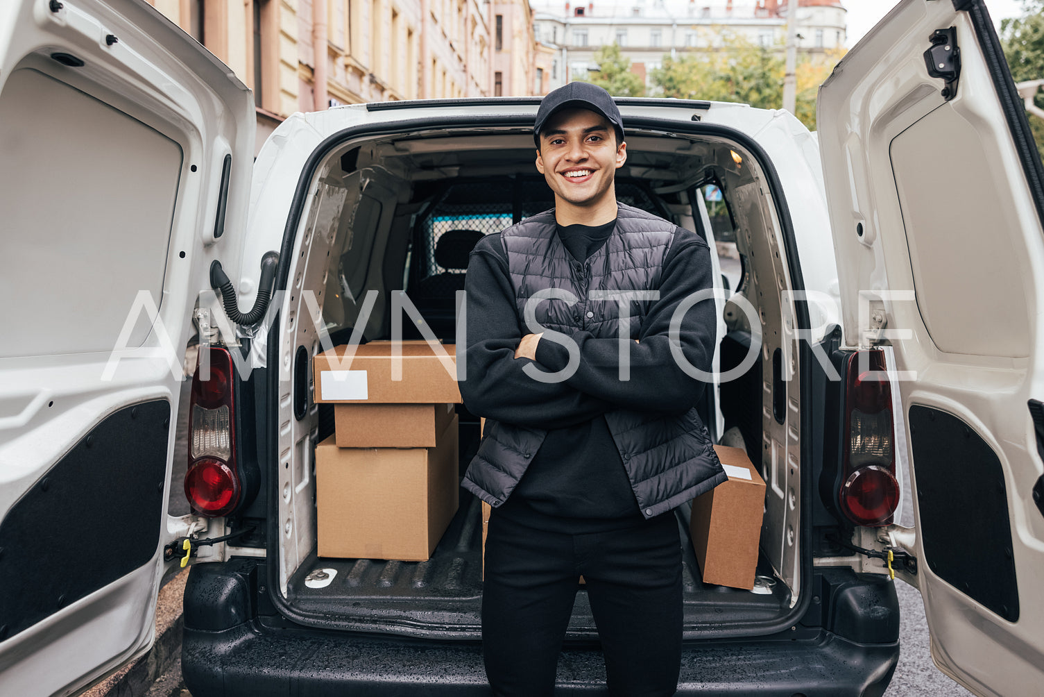 Portrait of a smiling delivery guy wearing a cap and uniform sta