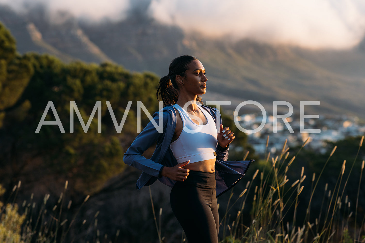 Confident female runner practicing outdoors at stunning sunset. Side view of slim woman in fitness attire jogging at sunset.