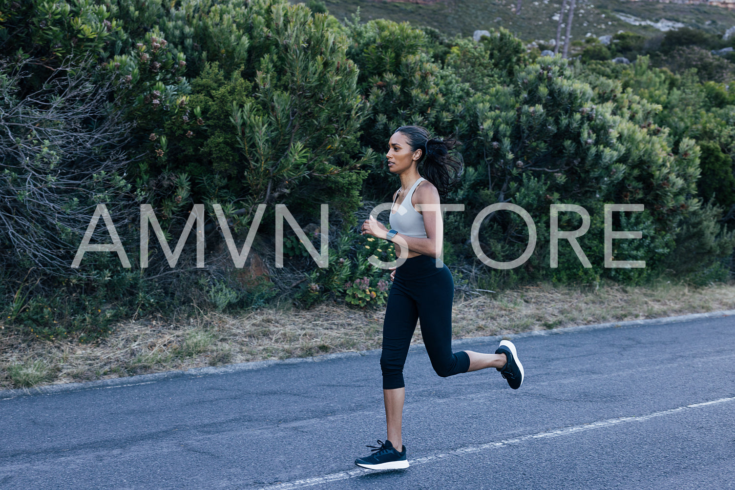 Full length slim female running in a natural park on an abandoned road 