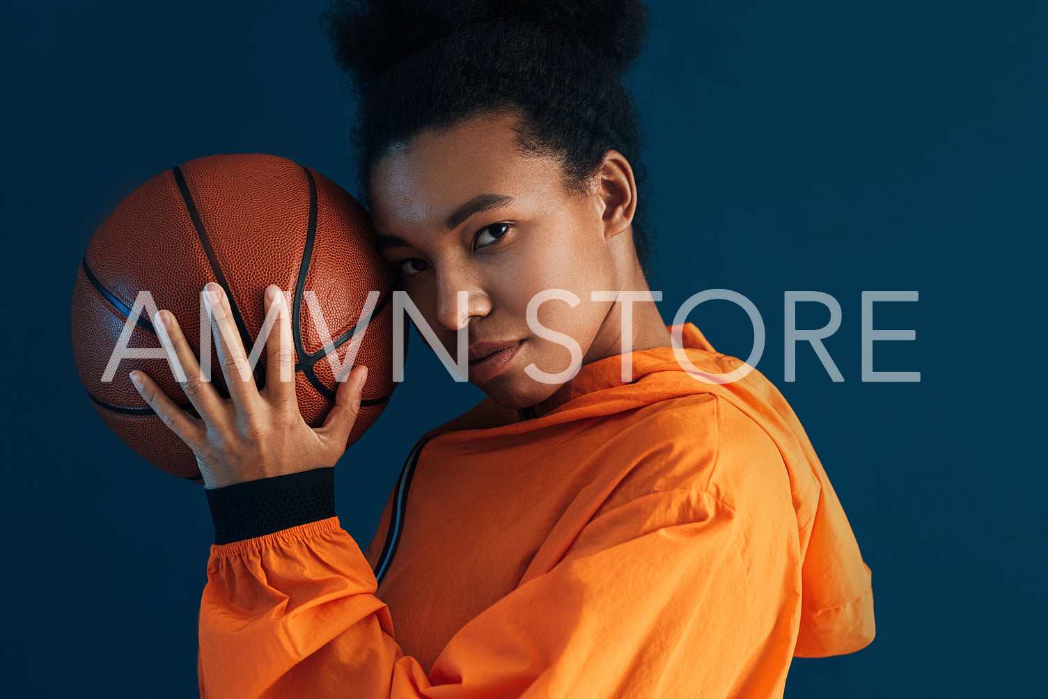 Portrait of a woman with a basketball against a blue backdrop. Studio shot of a confident female basketball player.