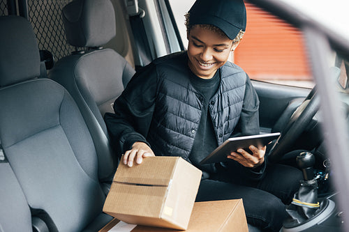 Young smiling woman in uniform checking the package for deliveri