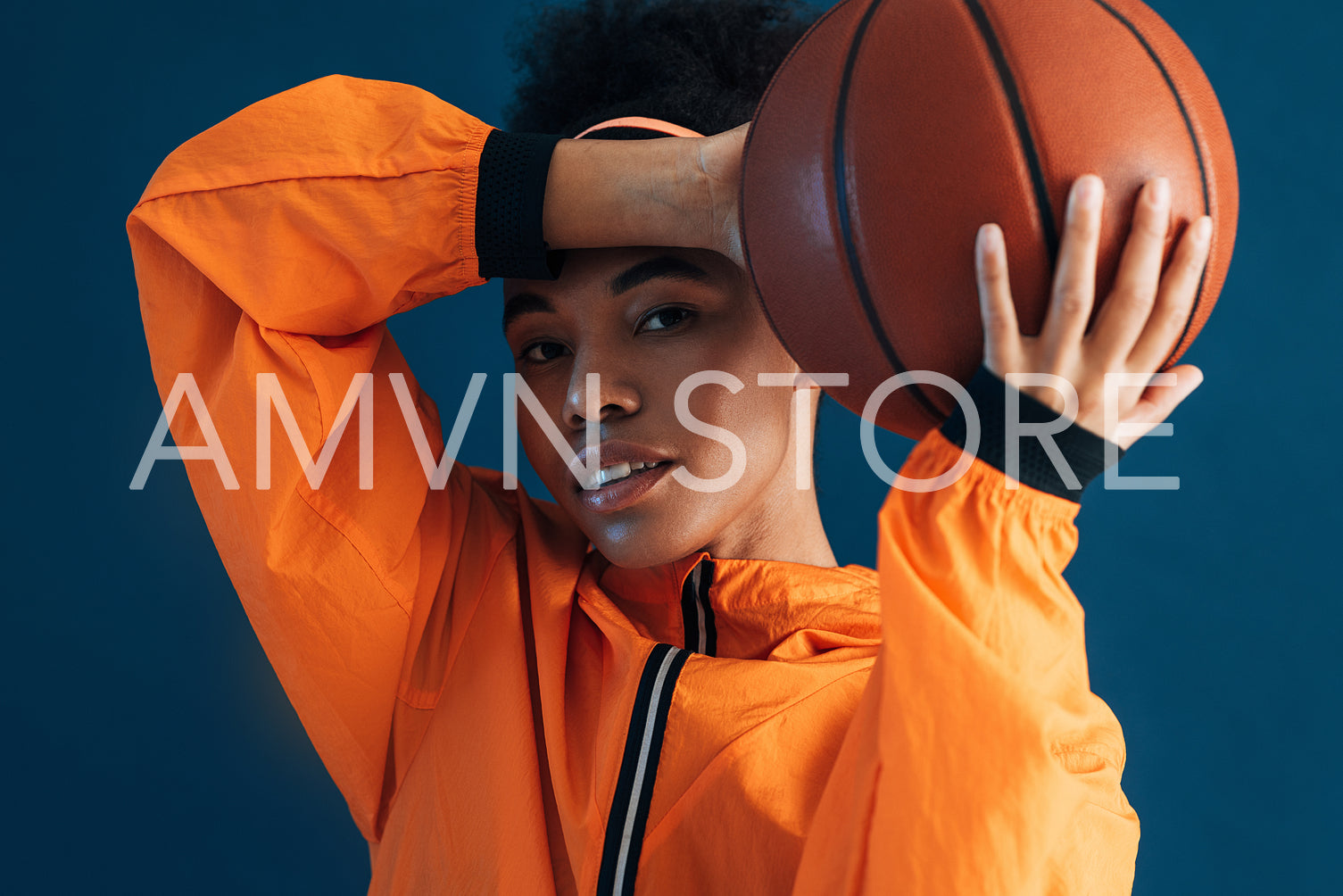 Close-up portrait of young female in orange clothes with basketball in studio