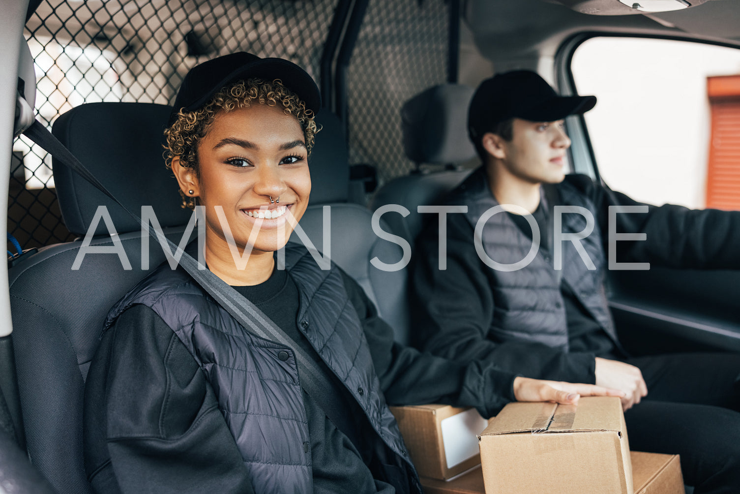 Smiling woman in uniform sitting in delivery van and looking at