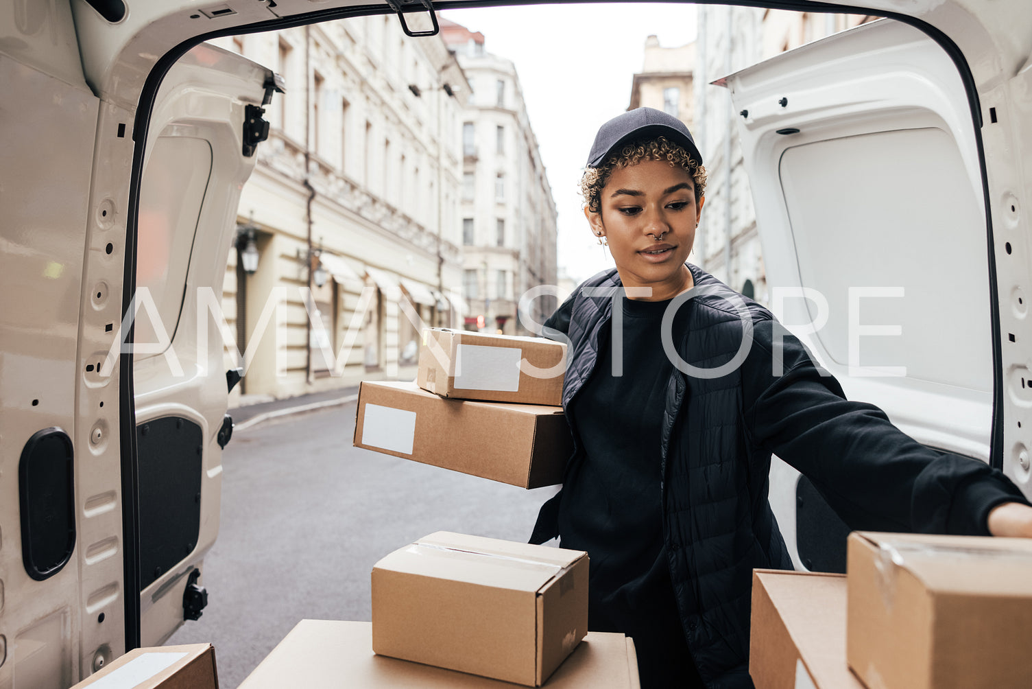 Delivery worker unloading cardboard boxes while standing at van