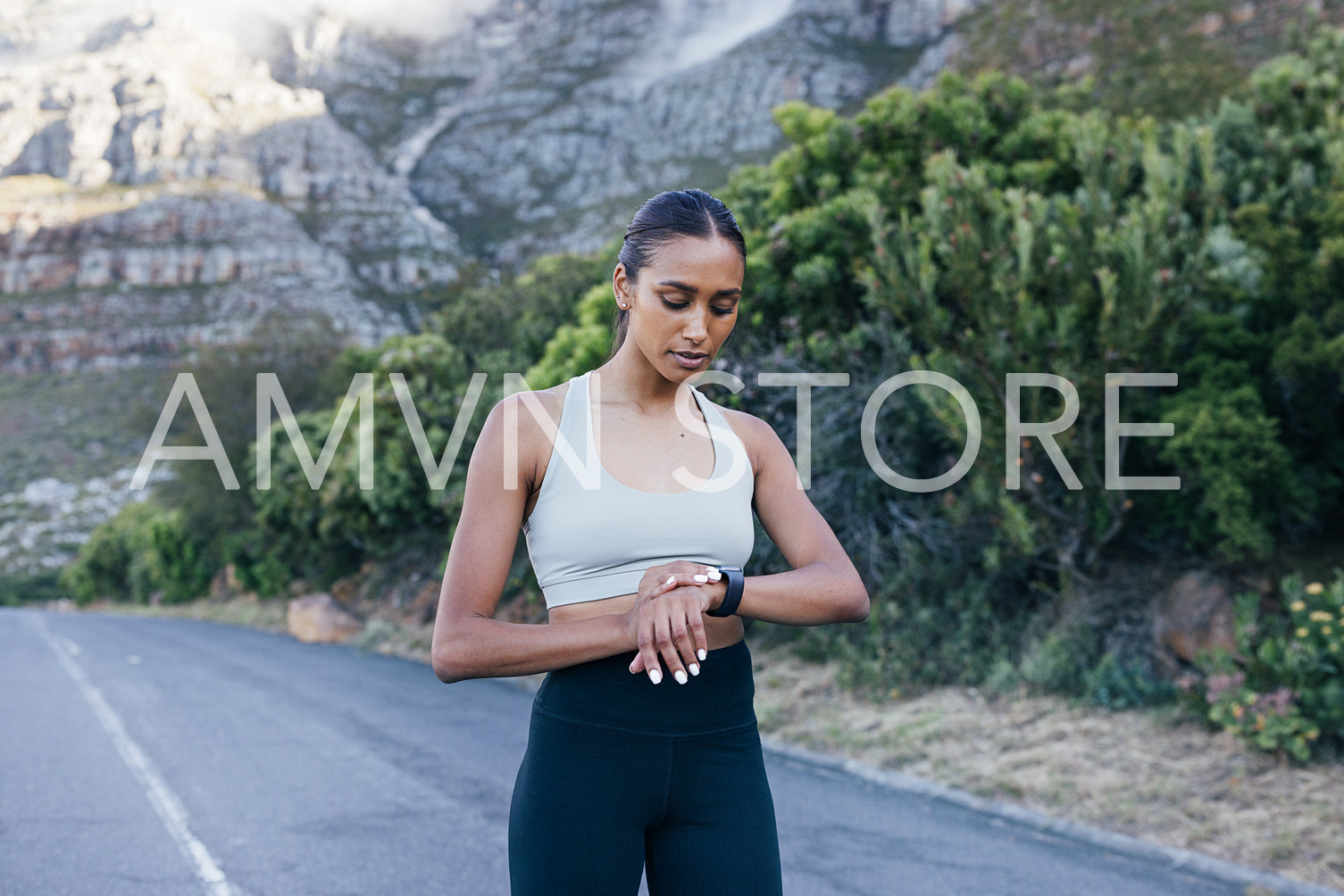 Sportswoman checking smartwatches. Young slim female checking pulse during a workout.