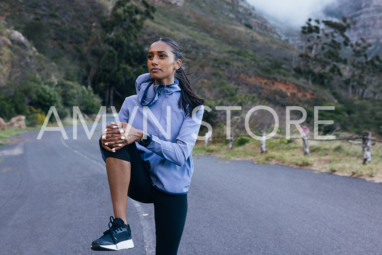 Slim confident female in fitness attire warming up her lower body on an abandoned road 