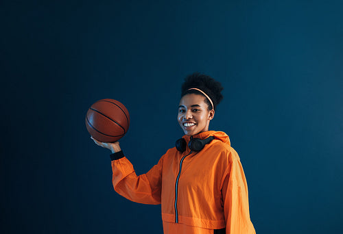 Portrait of a happy professional basketball player wearing orange fitness attire and looking at camera