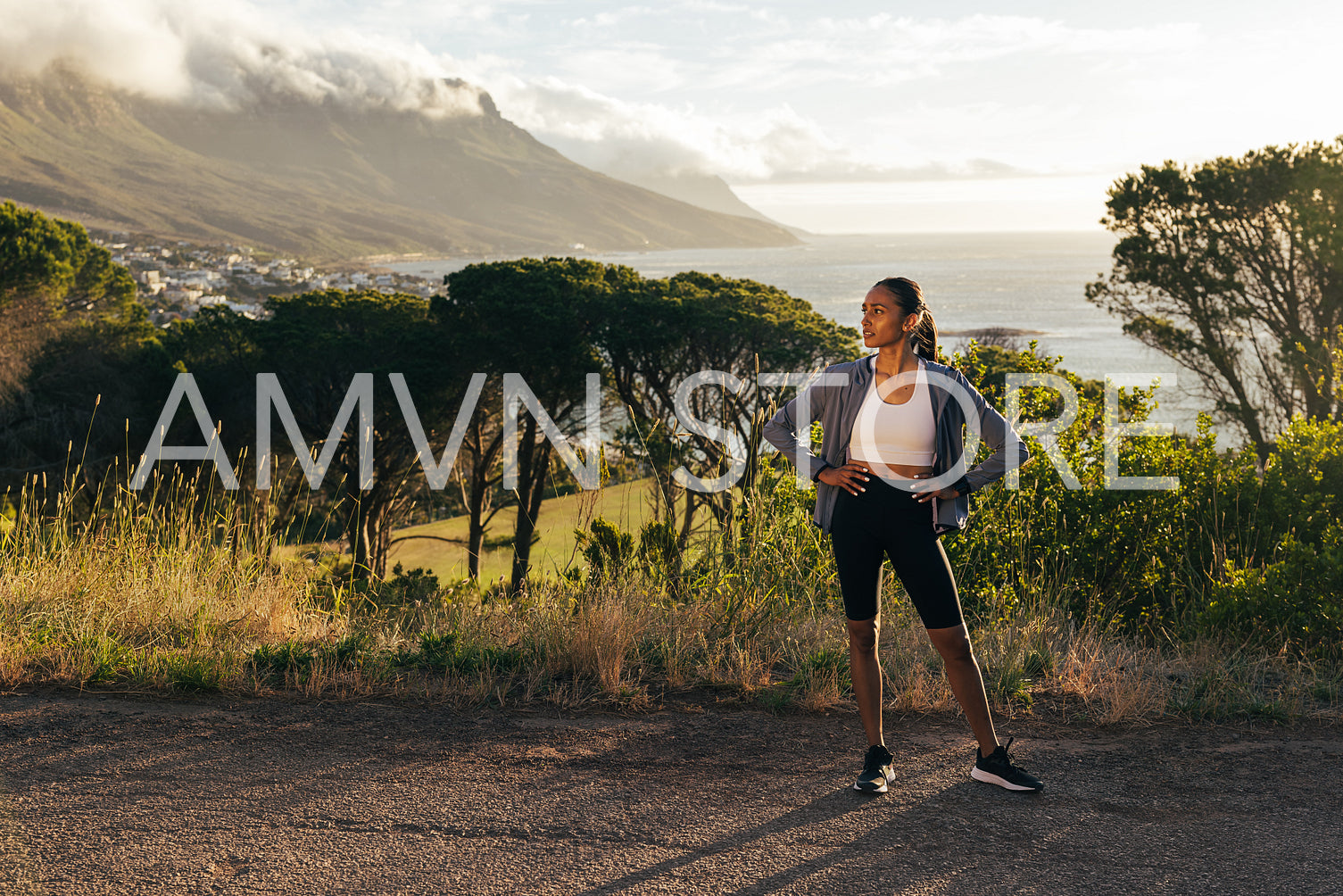 Confident female runner standing against a stunning view. Slim woman jogger relaxing during workout outdoors.