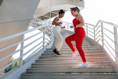 Two young females with different body types exercising together outdoors. Full length of two women doing a workout.