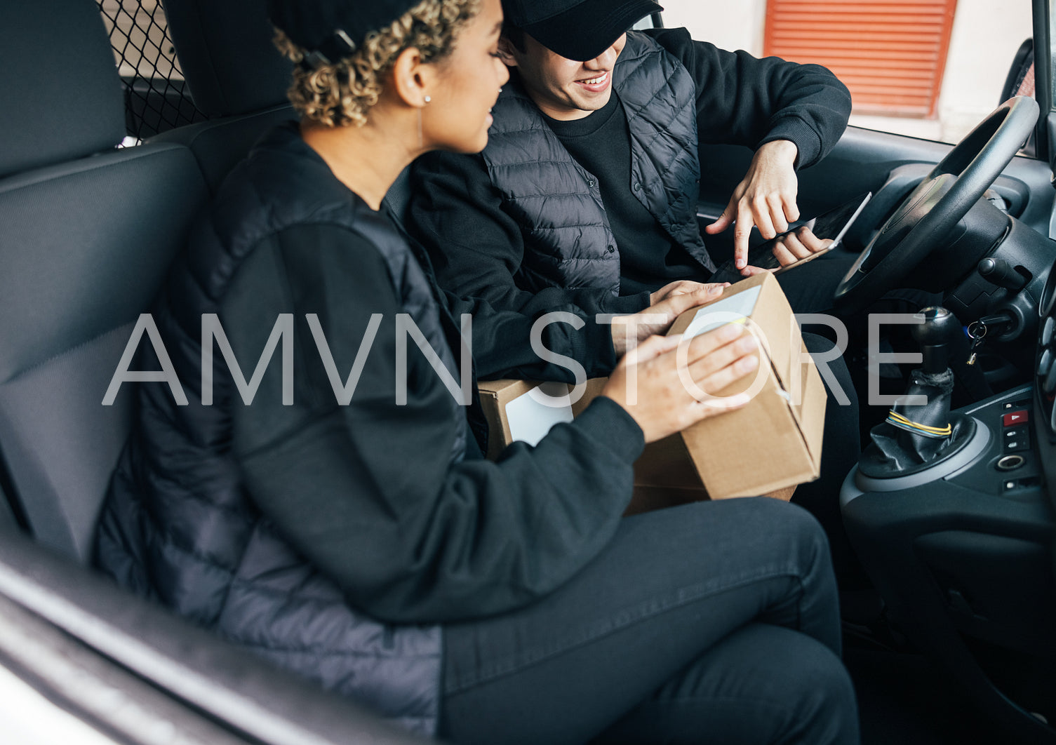 Two delivery coworkers in uniform checking information on cardbo