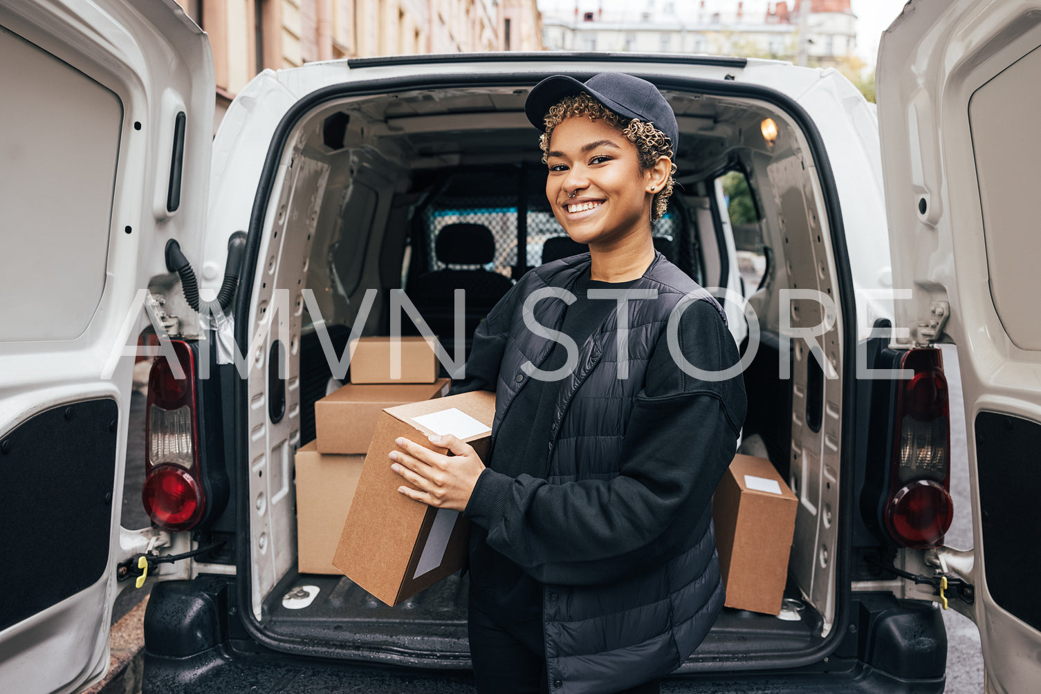 Portrait of a happy woman courier holding a cardboard box while