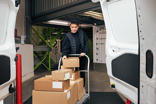 Woman in uniform checking cardboard boxes on a cart before putti