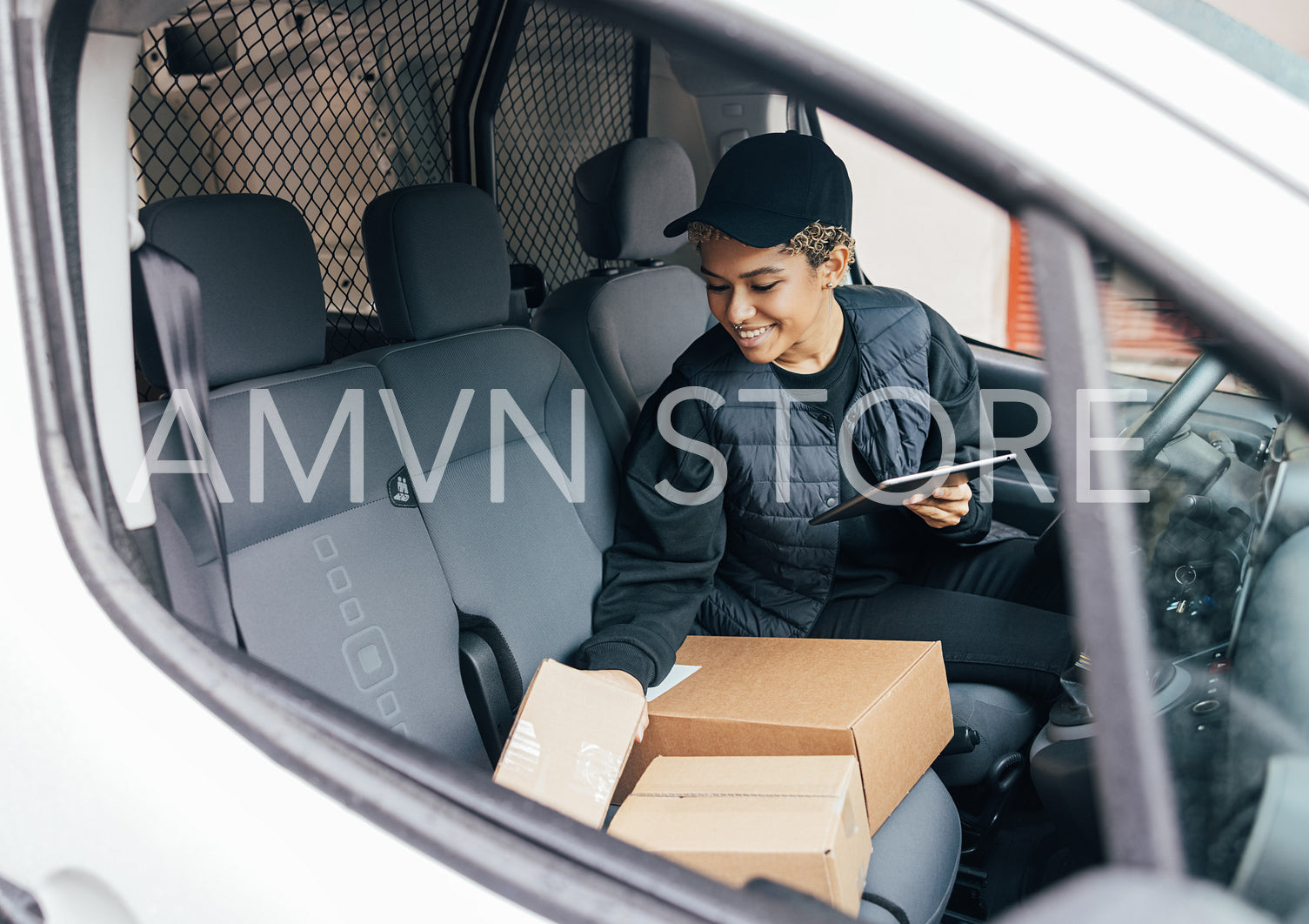 Smiling woman sitting on driver's seat checking packages and hol