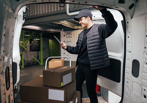 Young man holding a digital tablet while standing at van. Courie