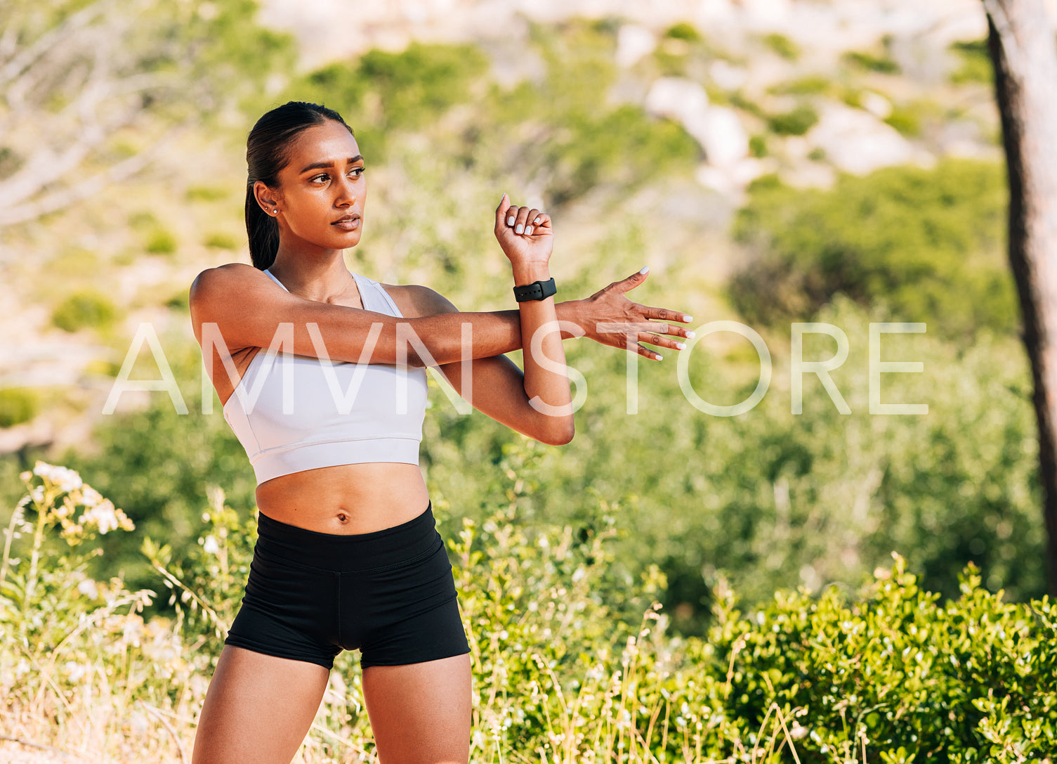 Slim female in fitness wear stretching her hand outdoors