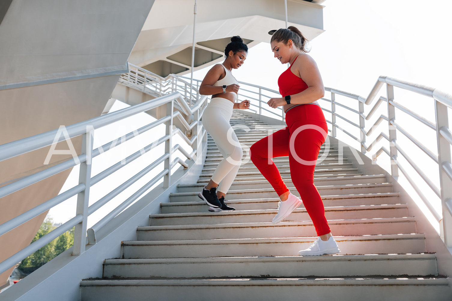 Two young females with different body types exercising together outdoors. Full length of two women doing a workout.