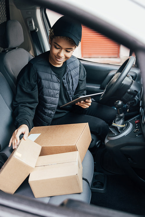 Woman courier checking information on a digital tablet while sit