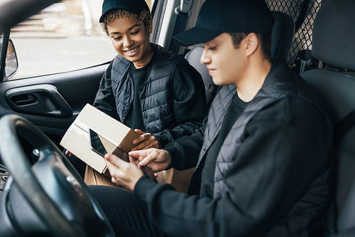 Two couriers in uniform sitting in a van checking delivery infor