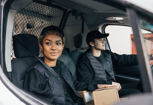 Two delivery coworkers in uniform sitting together in a van. Wom