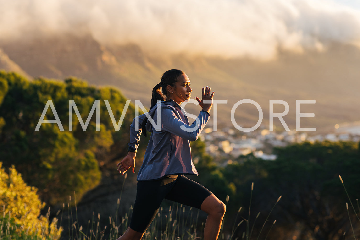 Young female running against mountains and clouds outdoors. Woman jogging outdoors with a stunning sunset in the background.