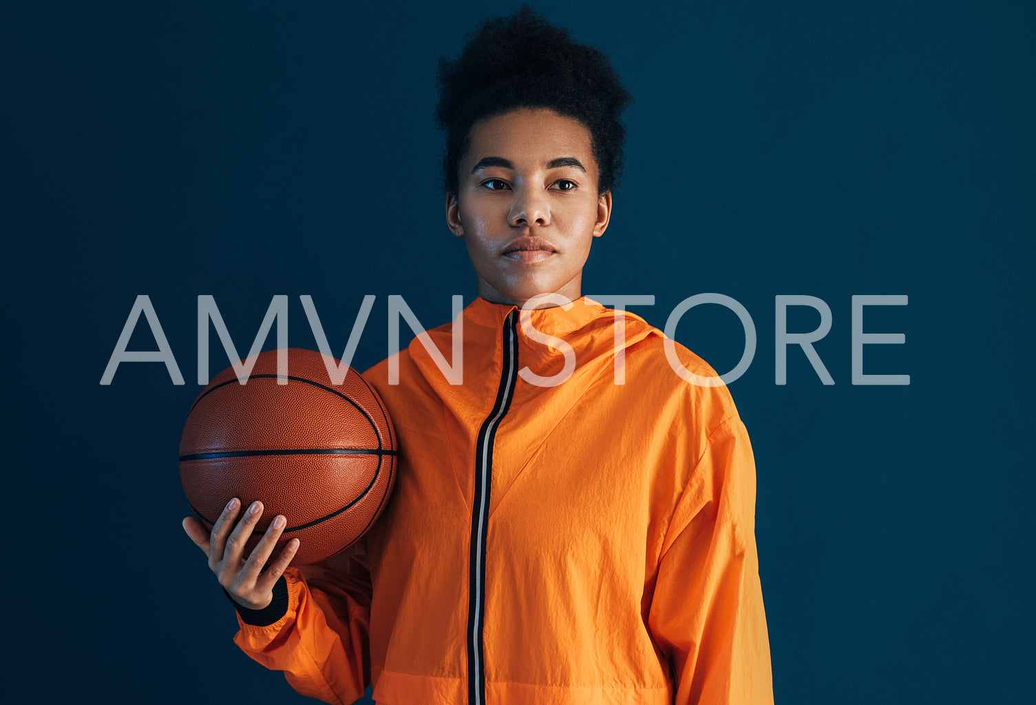 Portrait of a confident woman with basketball over blue backdrop looking away