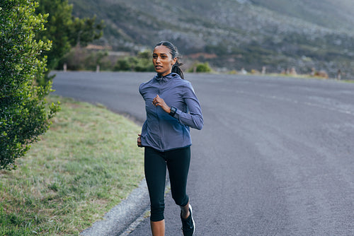 Slim woman runner on an abandoned road. Female in sportswear running on an empty road.