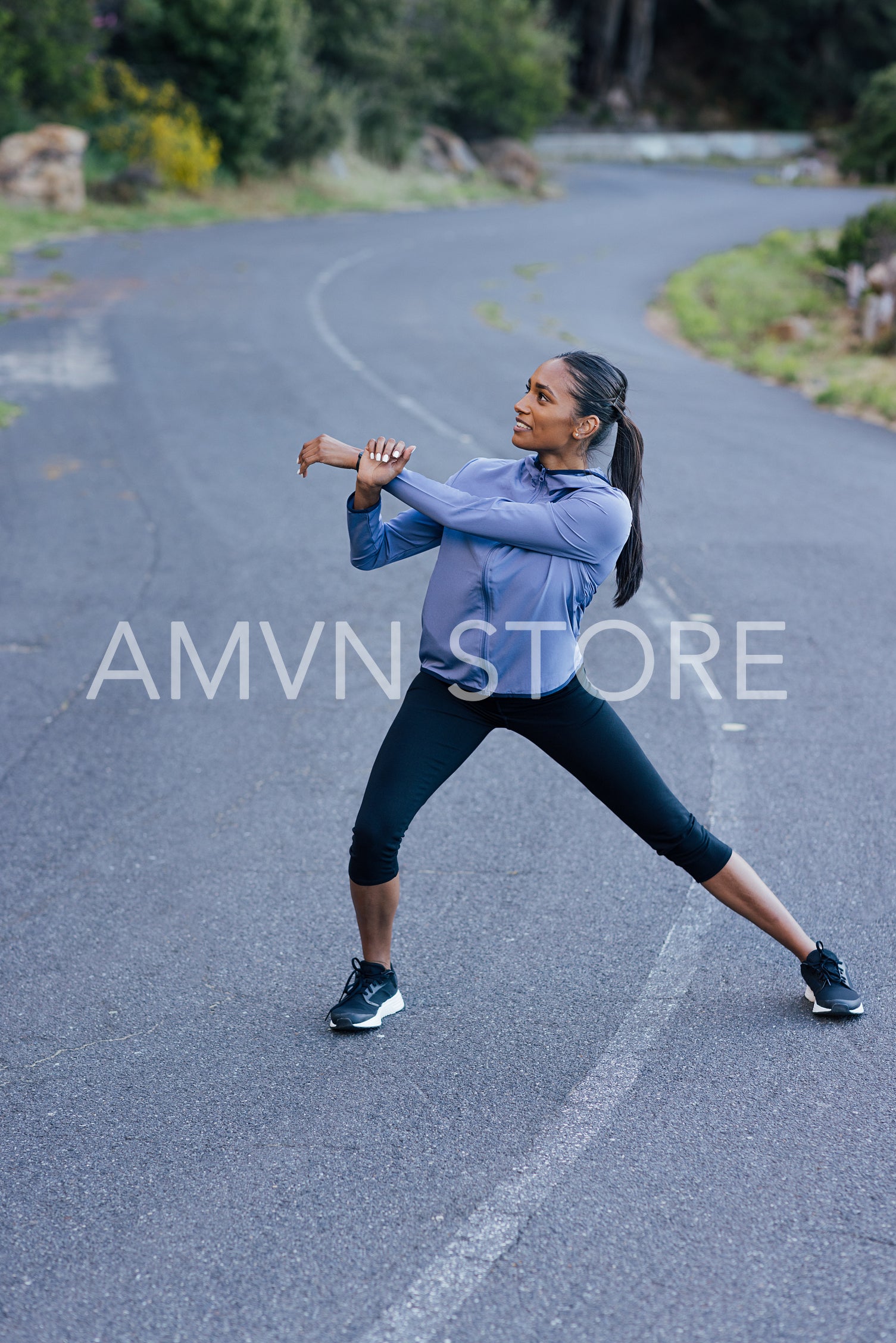 Young slim female warming up her body on an abandoned empty road 