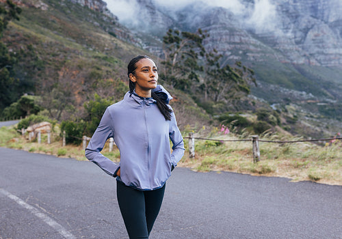 Young slim female in sportswear enjoying the view while walking. Woman doing morning walk in a natural park.