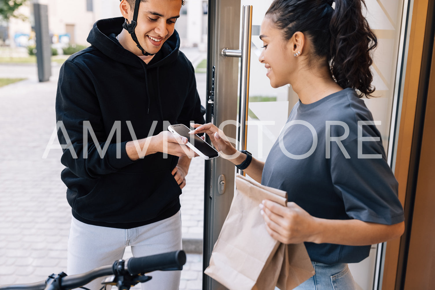 Woman receiving food delivery at the doorway. Young female signs for delivery on a smartphone.