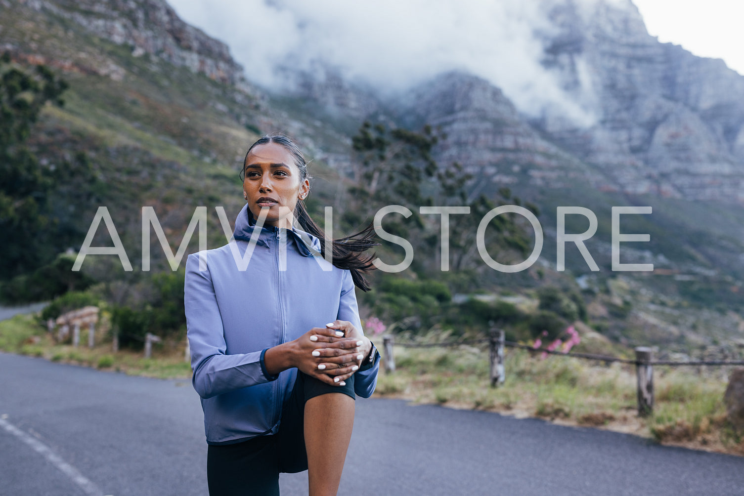 Young woman athlete warming up before workout in natural park. Confident sportswoman flexing leg outdoors.