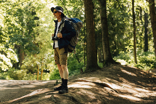 Full length of senior tourist wearing backpack and hat. Mature tourist looking for a place to camp.