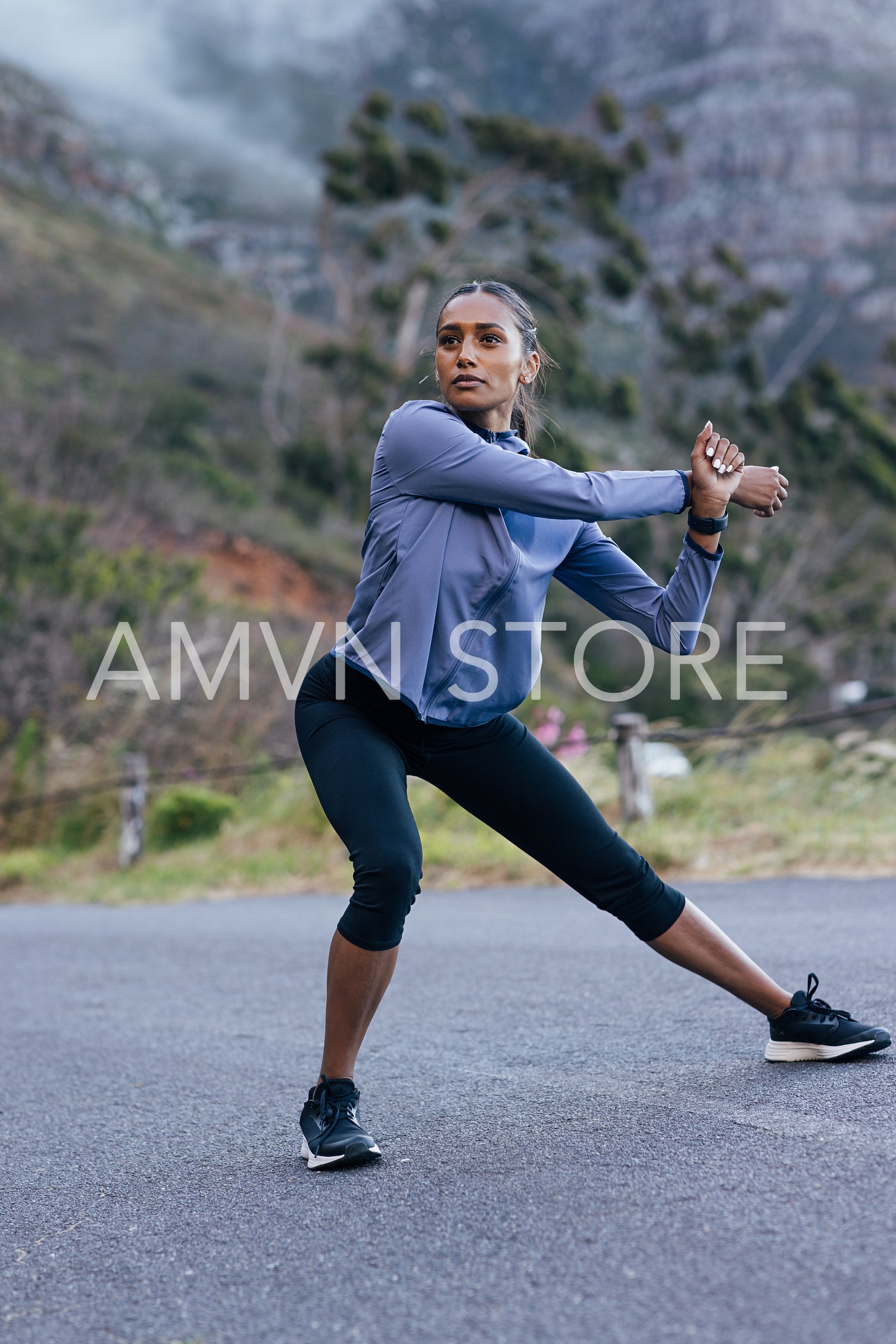 Confident female in sportswear warming up her body before outdoor run in natural park