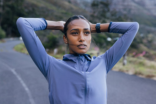 High-detailed portrait of a young female in sportswear and smartwatches on her wrist. Female relaxing after exercising in a natural park.