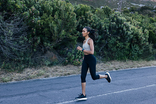 Full length slim female running in a natural park on an abandoned road