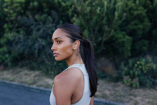 Portrait of a young woman athlete looking away. Young slim female posing outdoors while relaxing after exercise outdoors.