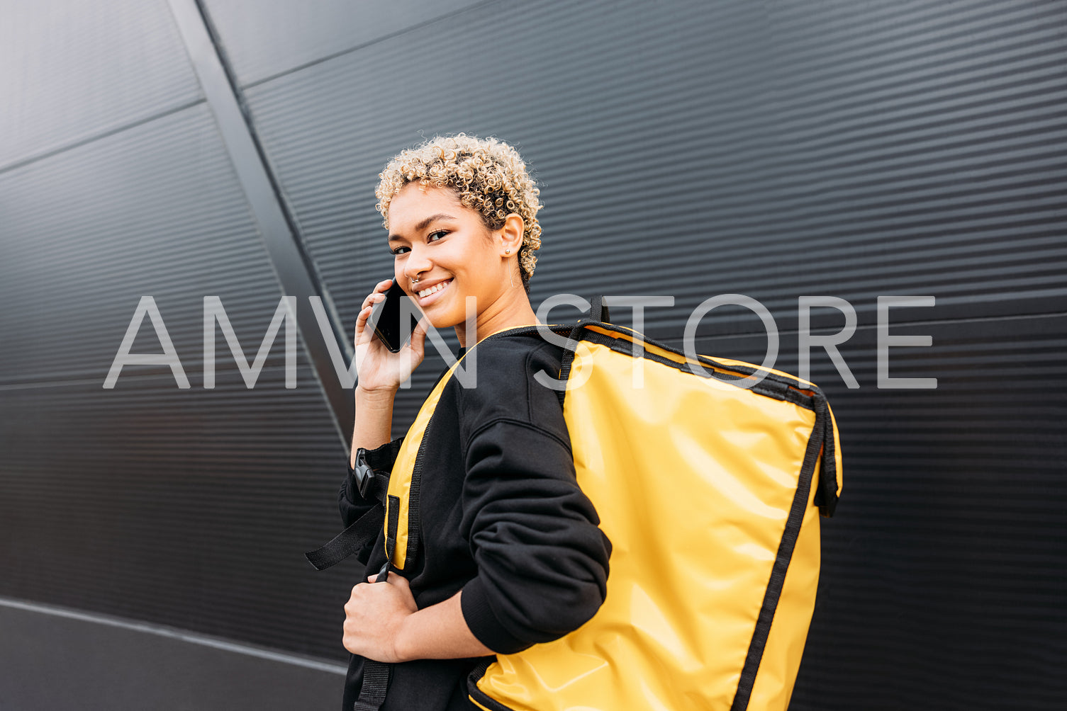 Woman courier with backpack talking on cellphone and looking at