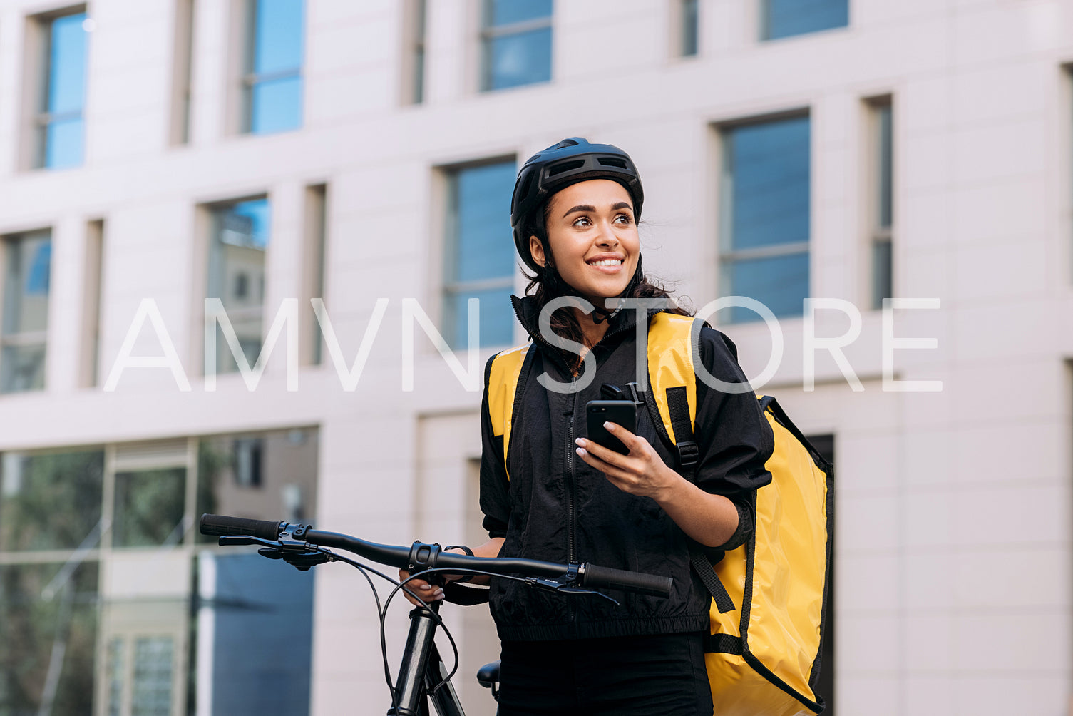 Food delivery woman using smart phone on street in city. Female courier in cycling helmet with backpack looking away.