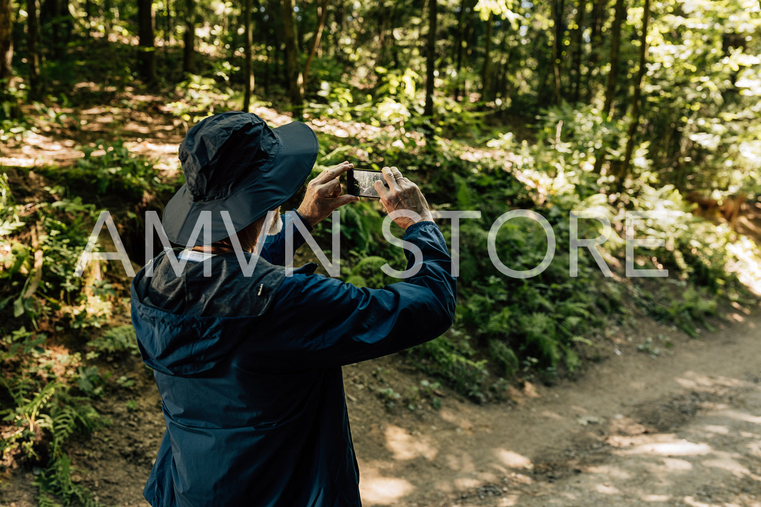 Back view of a male senior tourist taking photographs on his mobile phone during first walk