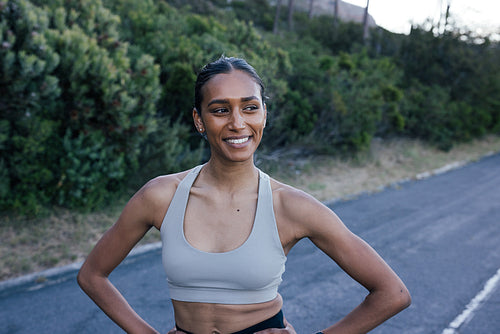 Portrait of a confident slim female looking away while relaxing during a workout in a natural park