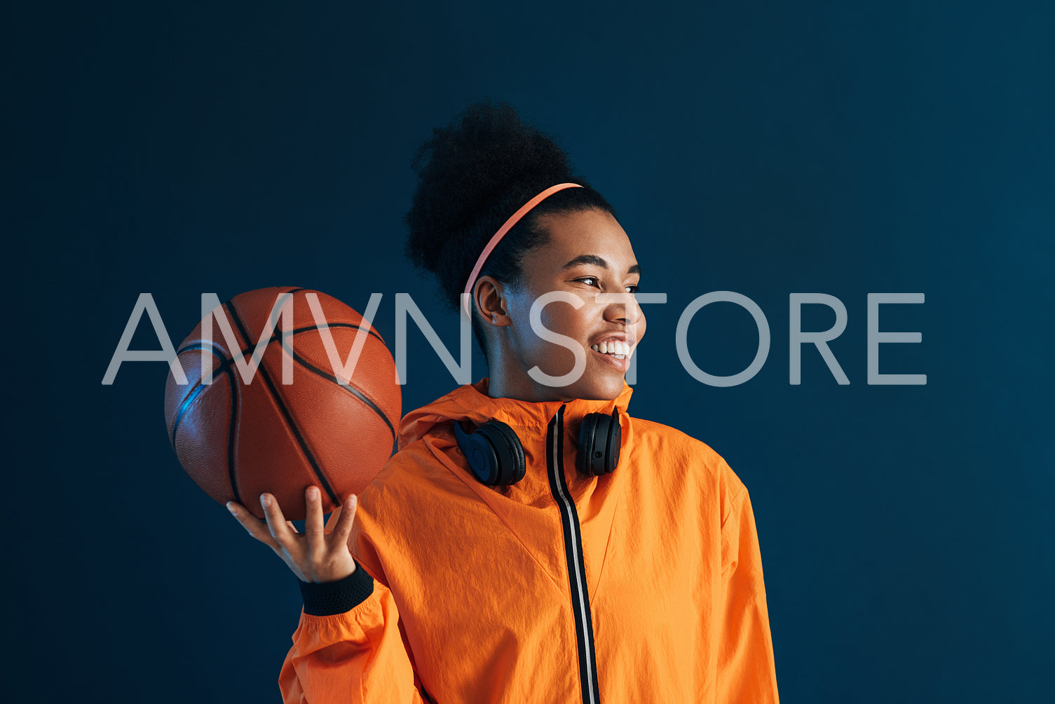 Smiling female basketball player with headphones looking away in the studio