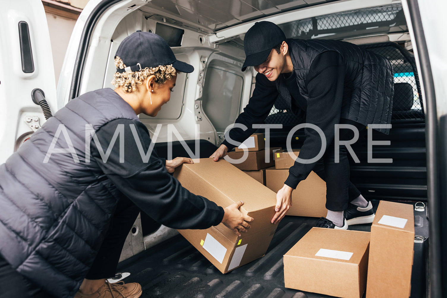 Two people working for delivery company unloading cardboard boxes from van