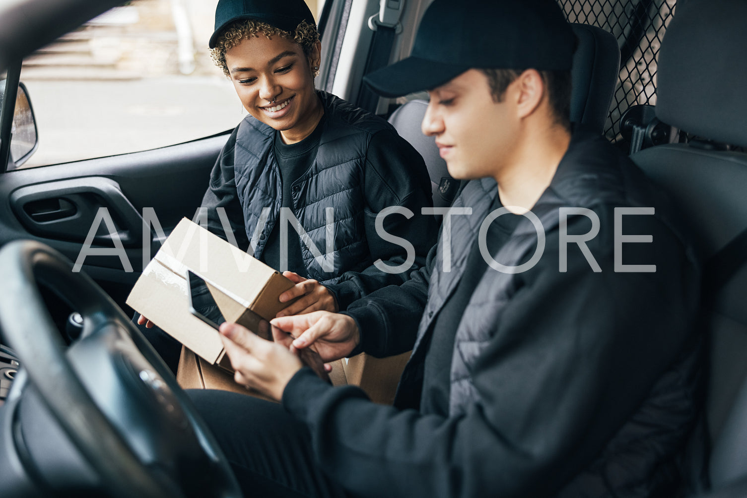 Two couriers in uniform sitting in a van checking delivery infor