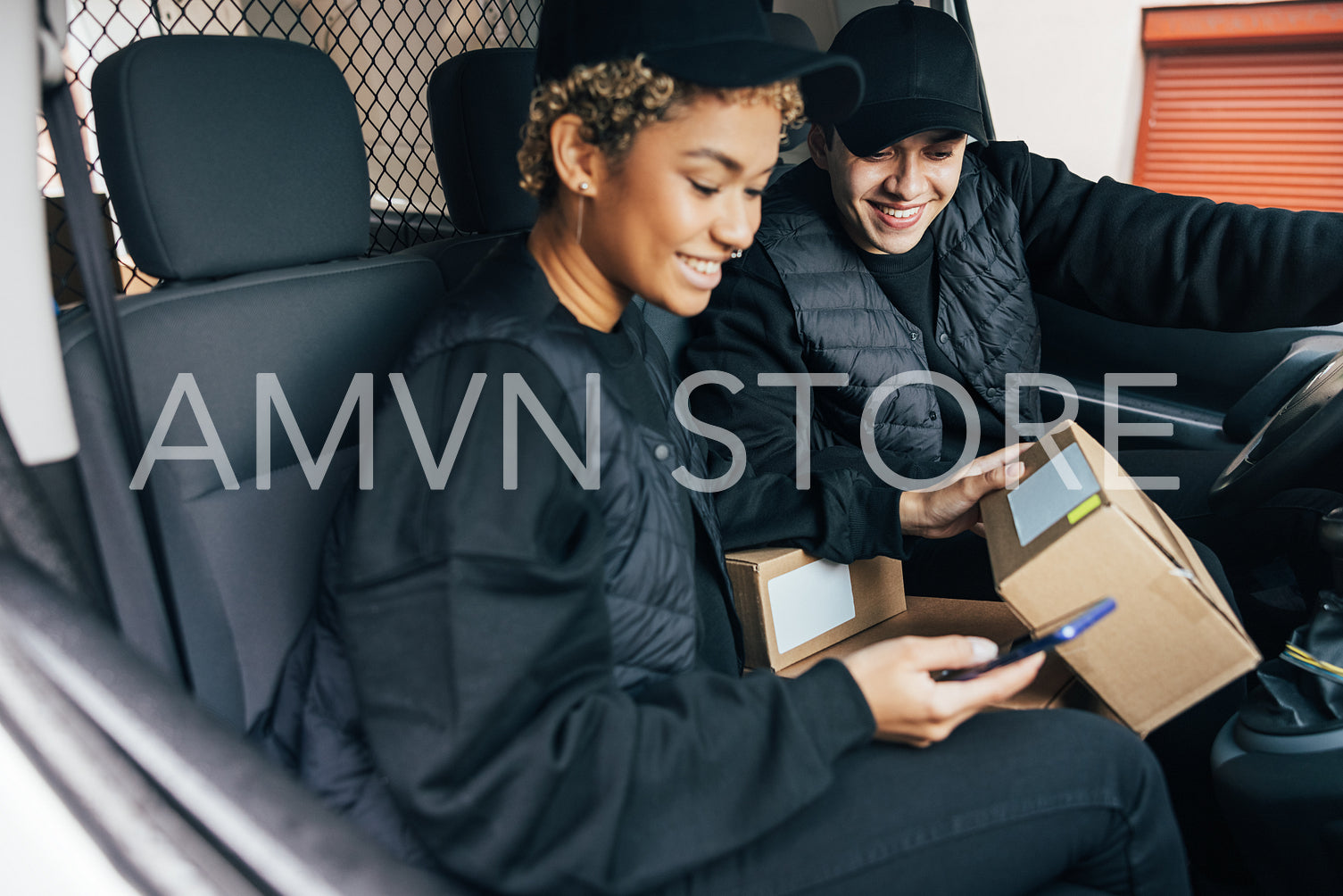 Two couriers sitting in car checking information on box using mo