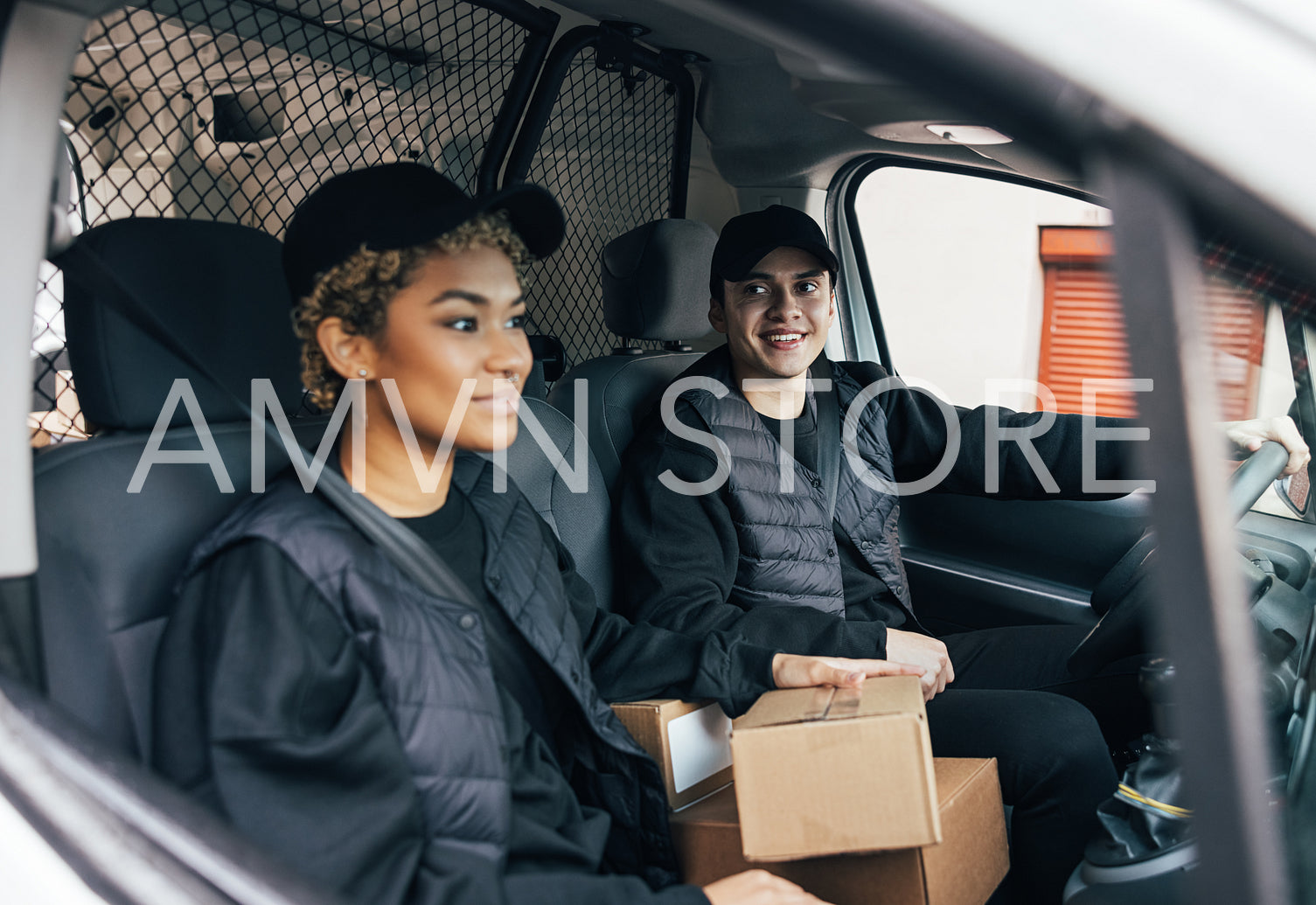 Delivery man looking away while sitting with a coworker in van